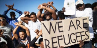 Rifugiati espongono cartello