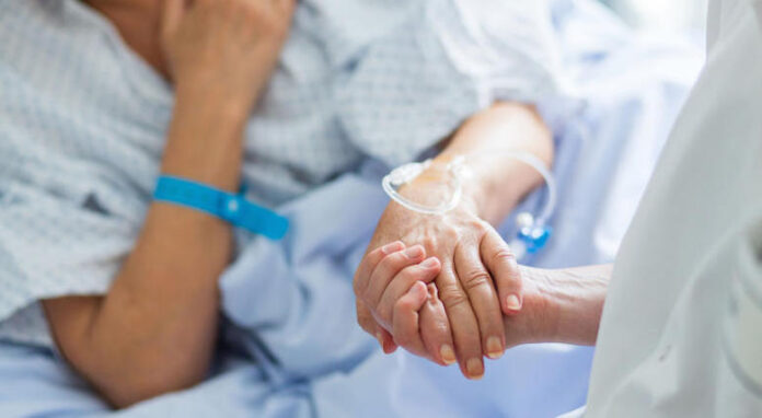 mano di una paziente nella mano di una persona che se ne prende cura
