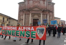 corteo con lo striscione della Divisione alpina Cuneense a Sant'Albano. Sullo sfondo la chiesa della confraternita