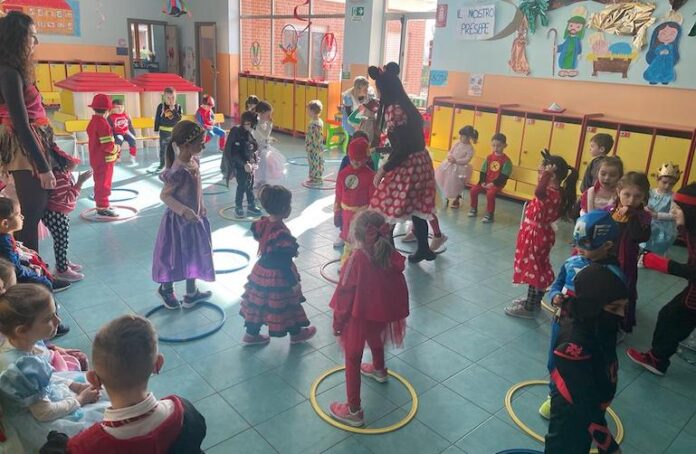 bambini della materna in costume mentre fanno u gioco con i cerchi nel salone della scuola