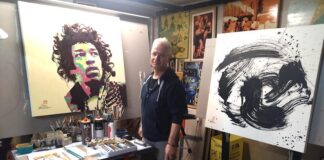 un pittore nel suo studio circondato da colori e quadri