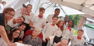 ragazzi e ragazze in camicia bianca con papillon rosso insieme agli anziani della casa di riposo