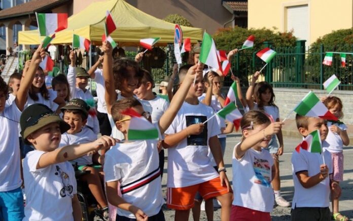 un gruppo di bambini mentre sventolano le bandierine dell'Italia